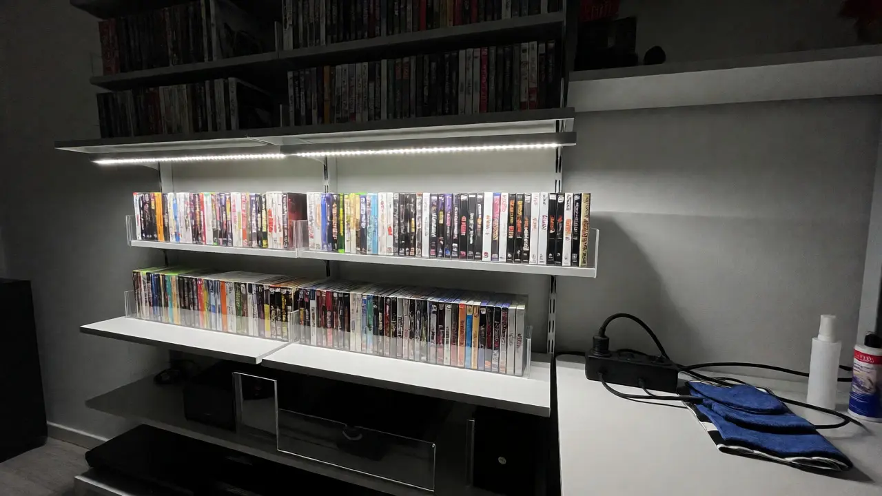 Organized shelves displaying vertical video game collections with protective cases and LED lighting.